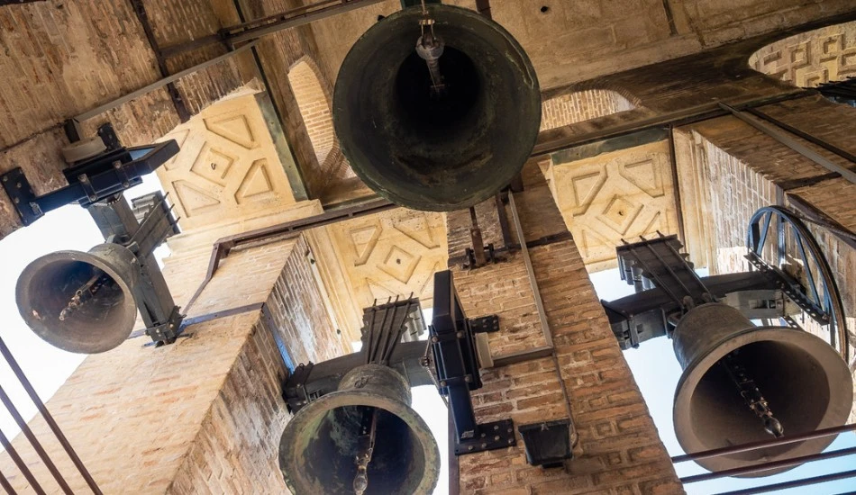 Bell tower view from below showing several large hanging bells and architectural details